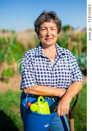 Mature woman having horticultural instruments in garden on day 72816964