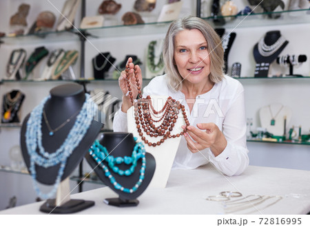 Female seller demonstrates golden stone necklace Female seller demonstrates golden stone necklace 72816995