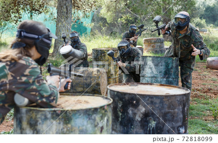 Two opposing teams playing paintball against each other in battle outdoors Two opposing teams playing paintball against each other in battle outdoors 72818099