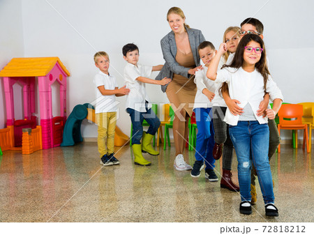 Positive female teacher playing circle game with children in classrom 72818212