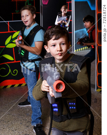 boy aiming laser gun at other players during lasertag game 72818724