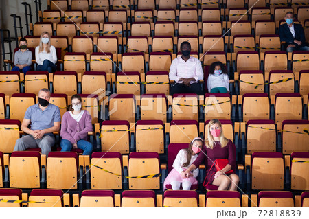 Spectators in protective masks sit in the theater hall observing social distance 72818839