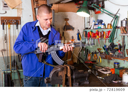 Gunsmith performing maintenance of Kalashnikov assault rifle in workshop Gunsmith performing maintenance of Kalashnikov assault rifle in workshop 72819609