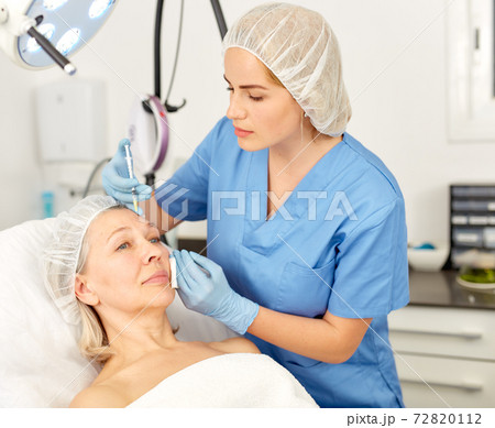 Senior woman getting injection for facial rejuvenation procedure in esthetic clinic 72820112