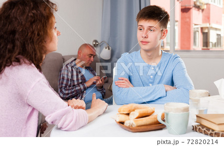 Boy talking to mother on background with indifferent father Boy talking to mother on background with indifferent father 72820214
