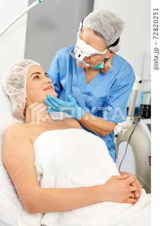Professional cosmetician examining face skin of girl in clinic of esthetic cosmetology Professional cosmetician examining face skin of girl in clinic of esthetic cosmetology 72820251