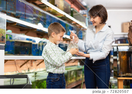 Boy and mother with fish in plastic bag Boy and mother with fish in plastic bag 72820507