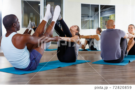 Women and men exercising in pairs during yoga class in modern fitness center Women and men exercising in pairs during yoga class in modern fitness center 72820859