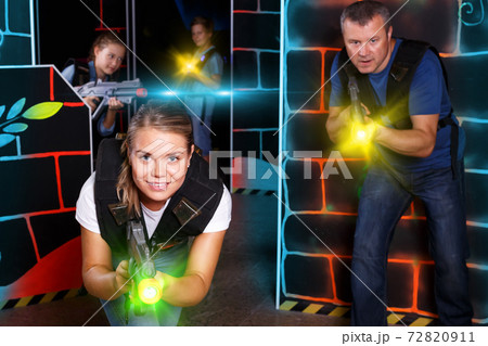 Woman playing lasertag with family Woman playing lasertag with family 72820911