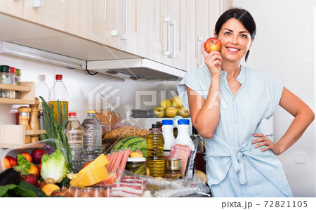 Portrait of cheerful woman with apple on the kitchen at home. 72821105
