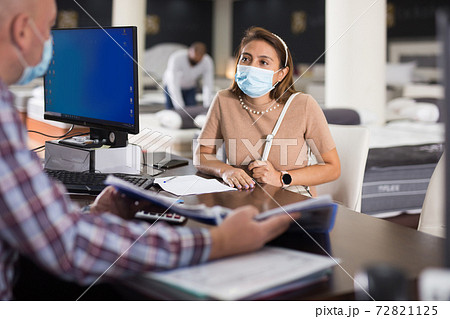 Hispanic woman in protective mask consulting with furniture salesman 72821125