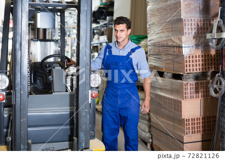 man in unifom is using сargo moving machine in the building store man in unifom is using сargo moving machine in the building store 72821126