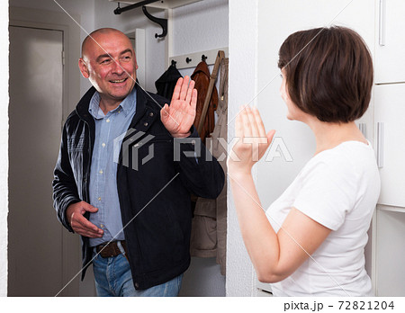 Husband says goodbye to her wife in the hallway of the apartment 72821204