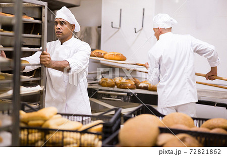 male baker rolling cart with bread in kitchen 72821862