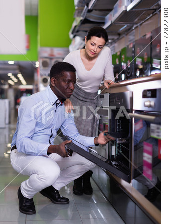 Couple selecting warming drawer in household appliance section in shop Couple selecting warming drawer in household appliance section in shop 72822300