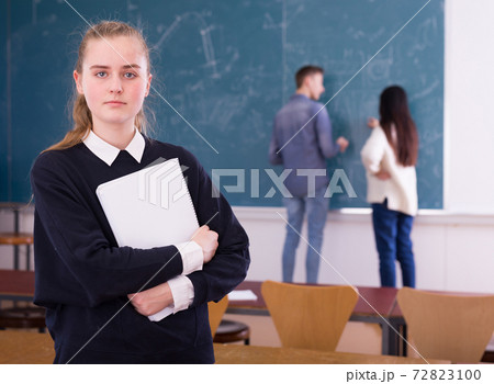 Portrait of girl student standing with notebook in classroom 72823100
