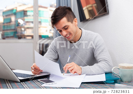 Smiling male with laptop analyzing domestic budget Smiling male with laptop analyzing domestic budget 72823631