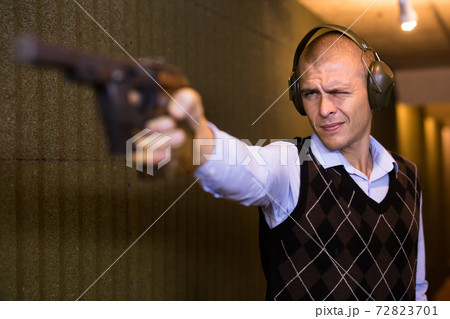 Shooter practicing sport handgun shooting at firing range Shooter practicing sport handgun shooting at firing range 72823701