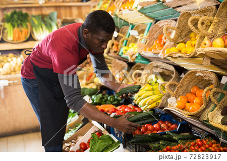Seller arranging vegetables and fruits on counter Seller arranging vegetables and fruits on counter 72823917