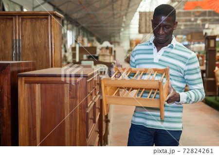 African American searching of wooden furniture in store 72824261