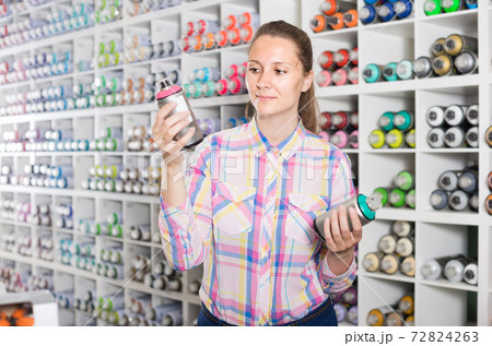 portrait of woman choosing paint color in aerosol can in art shop portrait of woman choosing paint color in aerosol can in art shop 72824263
