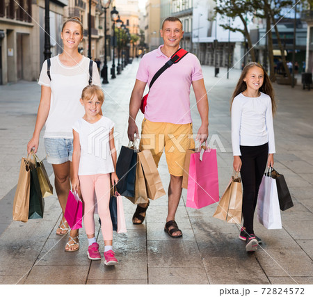 Man and woman with children walking and holding bags 72824572