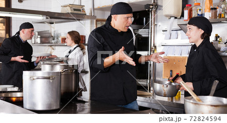 Chef male dissatisfied with the work of girl helper 72824594