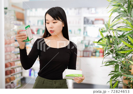 Young chinese female customer looking for right medicine in pharmaceutical store 72824653