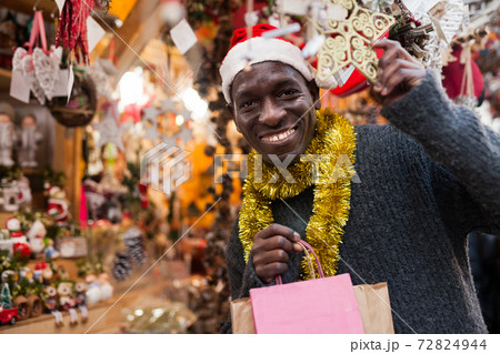 Smiling man in Santa hat selecting festive Christmas decoration 72824944