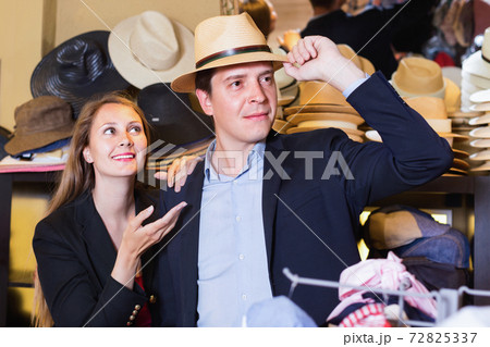 Girl and male try on modern hats at the boutique 72825337