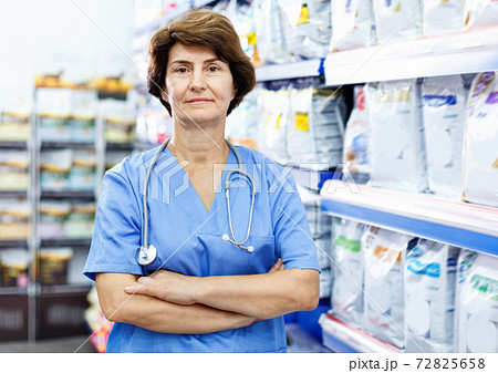 Portrait of confident elderly woman veterinarian standing near shelves with dog food in pet supplies store Portrait of confident elderly woman veterinarian standing near shelves with dog food in pet supplies store 72825658