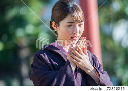 寒さで手に息を吹きかける着物女性の写真素材