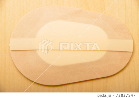 Band-aid for beige fabric eye isolated on wooden background Band-aid for beige fabric eye isolated on wooden background 72827547