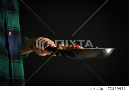 Woman holding pan with fried bacon on black background 72829931
