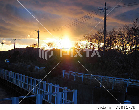 立ち込める雲の下の沈みゆく太陽の風景の写真素材