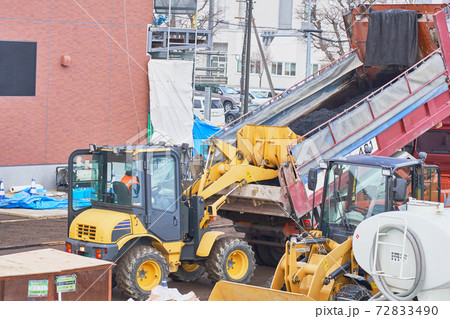 ダンプカーに積まれたアスファルトをタイヤショベルで運ぶ作業 72833490