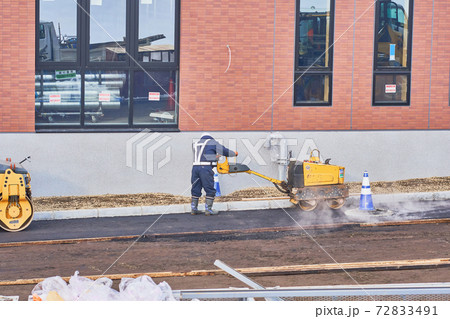 ハンドガイドローラーでアスファルトを締め固める作業 72833491