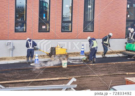 ハンドガイドローラーとプレートコンパクターでアスファルトを締め固める作業 72833492