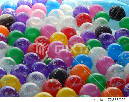 Small colorful plastic balls left floating in a small pond for children to play. Small colorful plastic balls left floating in a small pond for children to play. 72833765