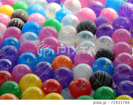 Small colorful plastic balls left floating in a small pond for children to play. Small colorful plastic balls left floating in a small pond for children to play. 72833766
