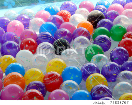 Small colorful plastic balls left floating in a small pond for children to play. 72833767