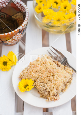 piece of cake with crumbs, tea and yellow flowers on white wooden background piece of cake with crumbs, tea and yellow flowers on white wooden background 72835550