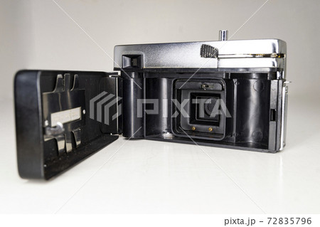 KODAPAK AUTOMATIC INSTANT LOAD CARTRIDGE 126 HALINA SIMPLETTE USA. Back with lid open of a compact analog camera in metallic black and white. White background. Horizontal photography. KODAPAK AUTOMATIC INSTANT LOAD CARTRIDGE 126 HALINA SIMPLETTE USA. Back with lid open of a compact analog camera in metallic black and white. White background. Horizontal photography. 72835796