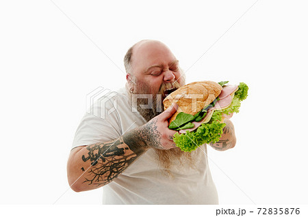 Hungry overweigh bearded man enjoying eating huge burger . Unhealthy food concept. 72835876