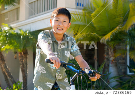 Young Asian boy on his bike in front of the house Young Asian boy on his bike in front of the house 72836169