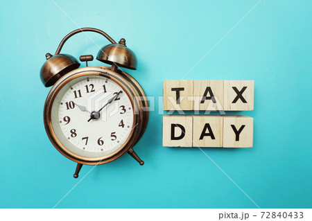 Tax Day Word alphabet letter And Alarm Clock on blue background Tax Day Word alphabet letter And Alarm Clock on blue background 72840433
