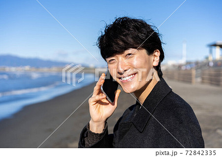 旅行先の海岸で電話をする男性 旅行先の海岸で電話をする男性 72842335