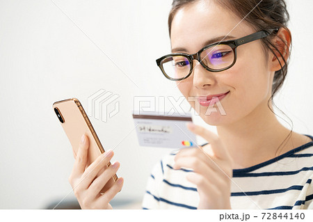 スマートフォンとカードを持つ若い女性 72844140