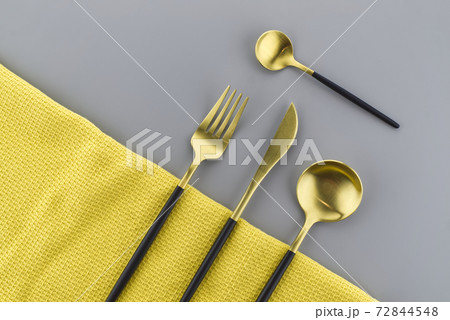 Black and gold cutlery on two tone grey and yellow 72844548