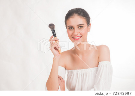 Smiling happily young woman is sitting holding a brush in hand on isolated white background. Smiling happily young woman is sitting holding a brush in hand on isolated white background. 72845997